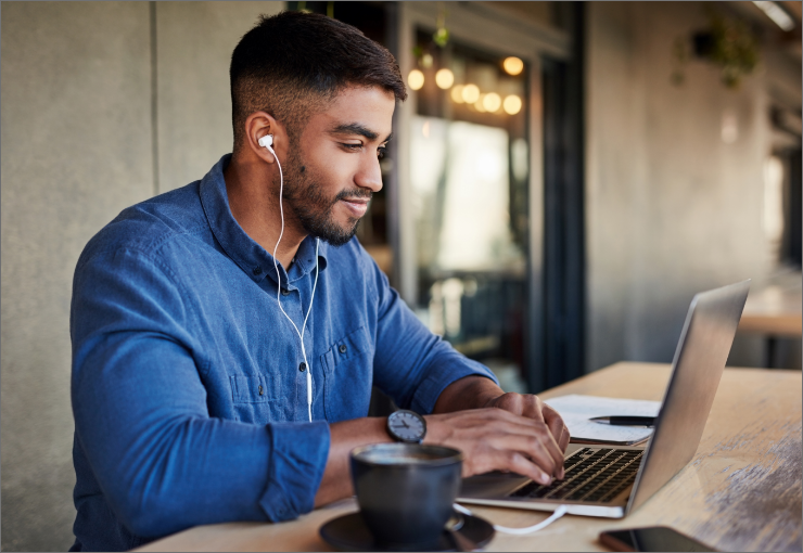man wearing earbuds using a laptop